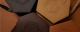 Explore our collection of eumelanin-inspired, stylish hexagonal leather bags in shades of black, brown, tan, and mustard. Each bag features an embossed geometric design on the front and is artfully arranged against a brown background.